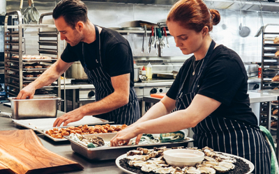 Two people cooking food in a commercial kitchen